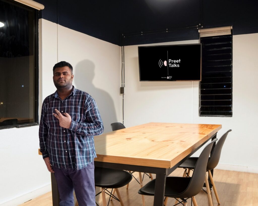 Lovepreet Singh, a young cyber security entrepreneur, sitting at a desk with computers and security imagery in the background.